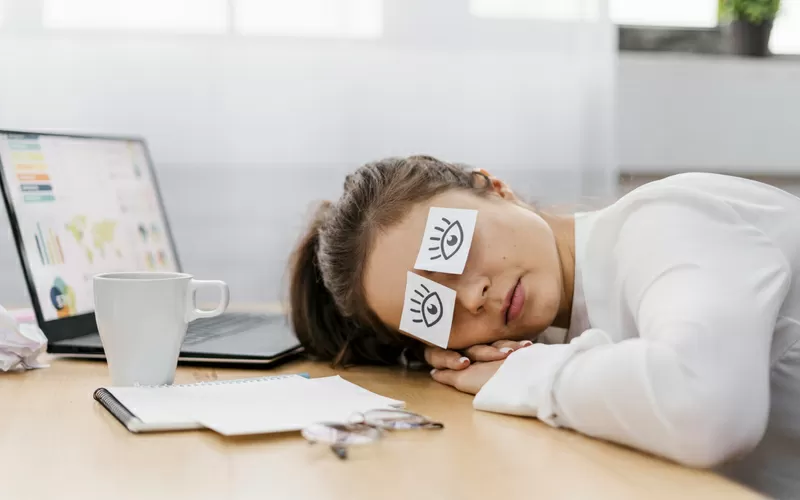 Imprenditrice stanca che copre gli occhi con gli occhi disegnati su carta